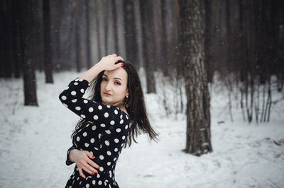 Portrait of beautiful woman standing in forest during winter