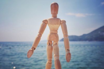 Close-up of wooden figurine against sea