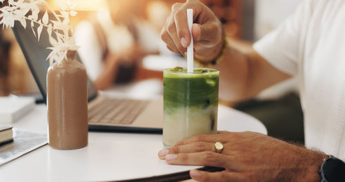 Midsection of man holding drink on table