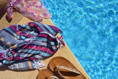 High angle view of scarf by flip-flops at poolside