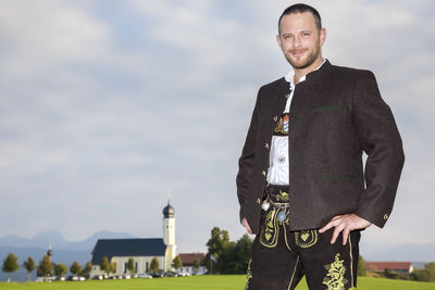 Portrait of man in traditional clothing standing against sky