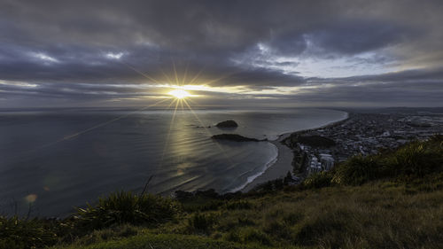Scenic panoramic view of sea against sky during sunrise with bay and city at base of hill