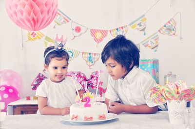 Cute siblings looking at birthday cake in living room