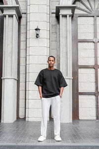 Portrait of young man standing against wall