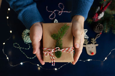 Man wraps a handmade eco style christmas present in kraft paper and natural spruce branches 