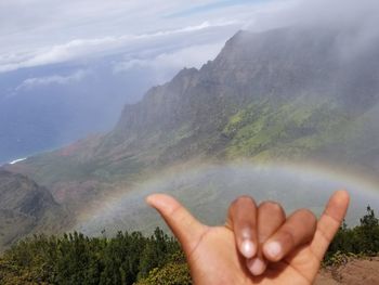 Close-up of hands against sky and clouds