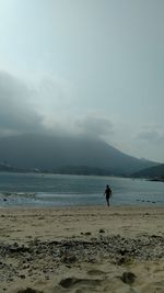 Man walking on beach against sky