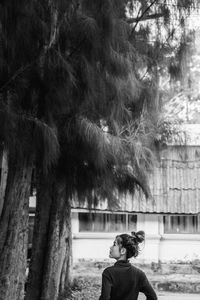 Rear view of man standing by tree trunk