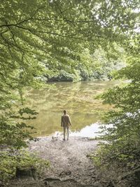 Rear view of man standing at lake in forest