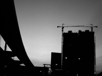 Low angle view of silhouette crane against clear sky