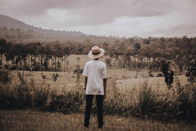 Rear view of man standing on field against sky