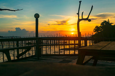 Silhouette pier over sea against sky during sunset