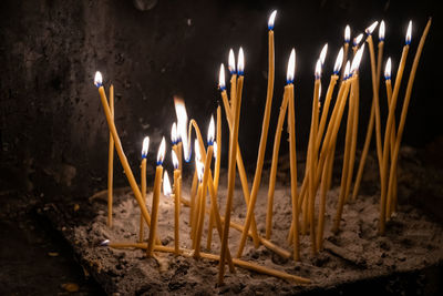 Close-up of burning candles in temple against building