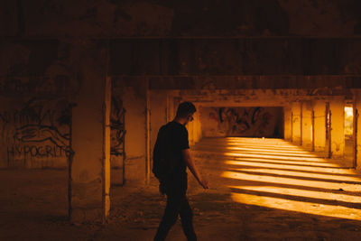 Side view of silhouette man walking on illuminated street at night