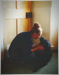 Side view of woman with black labrador at home