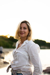 Portrait of smiling woman standing against sky