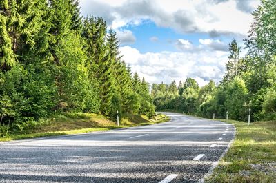 Road amidst trees in forest against sky