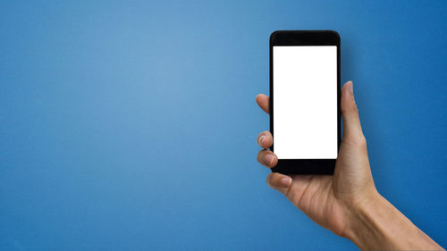 Midsection of person holding smart phone against blue background