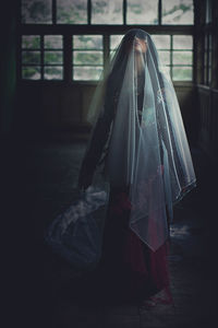 Woman covered with fabric standing in room