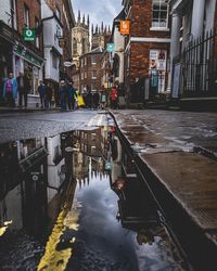 Wet street amidst buildings in city during rainy season