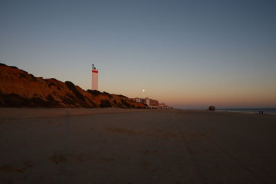 A lighthouse at the beach on sunset.