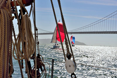 Sailboat hanging on bridge over sea against sky