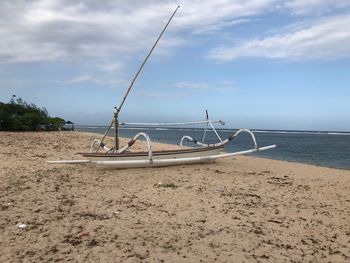 Sailboats moored on beach against sky