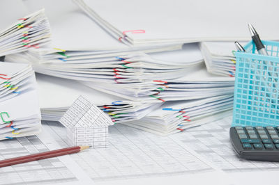 Close-up of model house with calculator and pencil on financial documents