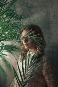 Woman with plant against wall