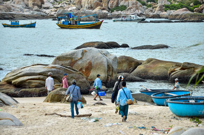 People walking on rock by sea