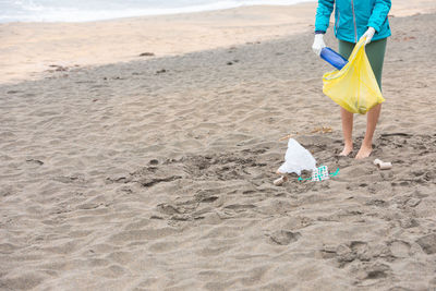 Low section of woman standing at sandy beach