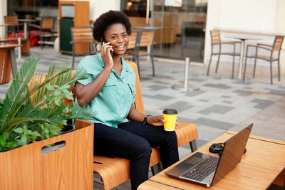 Portrait of woman talking over mobile phone while sitting at outdoor cafe