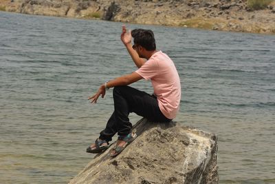 Side view of man on rock by sea