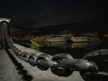 Close-up of boats moored at harbor against sky at night