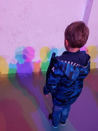 Rear view of boy against multi colored wall