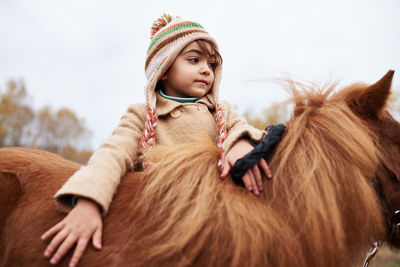 Beautiful girl touching chestnut pony