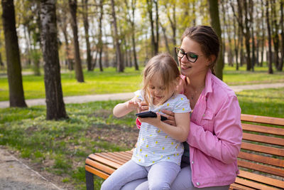 Mom looks over her shoulder at what her daughter has found on her smartphone.