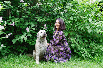 Portrait of woman with dog sitting by plants