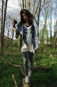 Portrait of young woman standing against trees