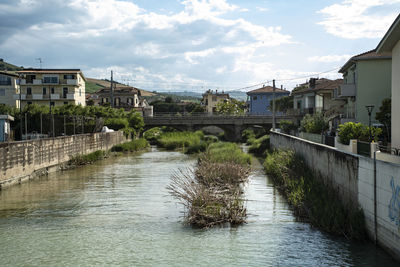 Bridge over river amidst buildings against sky