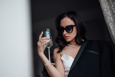 Portrait of young woman holding sunglasses