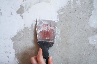 Midsection of person holding ice cream against wall