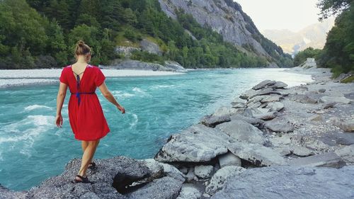 Woman walking on rocks at riverbank