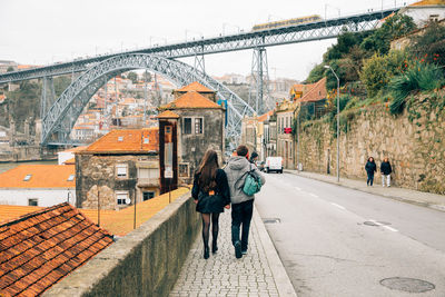 Rear view of couple walking on footpath towards dom luis i bridge