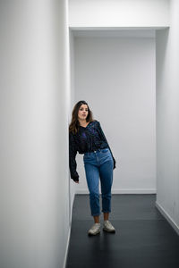 Portrait of woman leaning against wall in corridor 