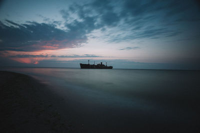 Silhouette boat in sea against sky during sunset