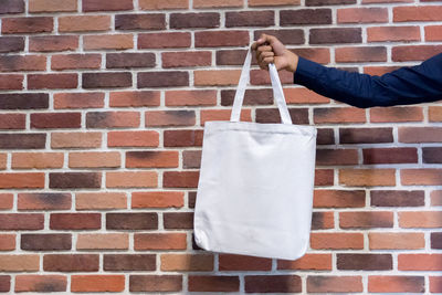 Man holding umbrella against brick wall