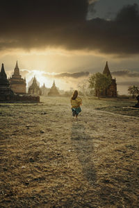 Man in temple by building against sky during sunset