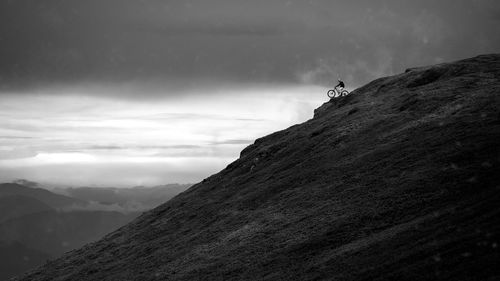 Scenic view of mountains and mtb rider against sky