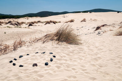 Footprints on sand dune in desert against sky